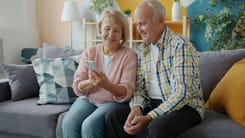 Pensioniertes Ehepaar sitzt auf dem Sofa in ihrem Eigenheim. 