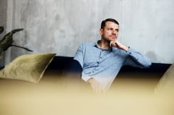 Mann im modernen Wohnraum steht für Themen wie Erbschaft, Vermögensübertragung und langfristige Finanzplanung.