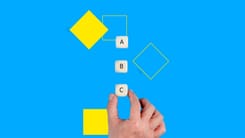 Hand hält Würfel mit Buchstaben A, B, C vor blauem Hintergrund mit gelben Formen