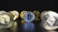 Symbolische Darstellung verschiedener Kryptowaehrungen mit Bitcoin im Vordergrund auf dunklem Hintergrund.