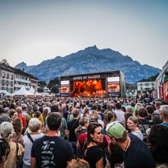 Konzertbesucher vor der Bühne des Sound of Glarus Festivals mit Bergkulisse in der Abenddämmerung