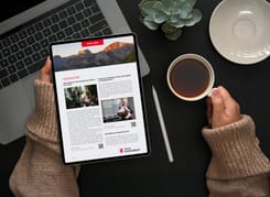 Tablet zeigt digitalen GLKB-Newsletter vom April 2026 auf einem Schreibtisch mit Kaffee und Stift.