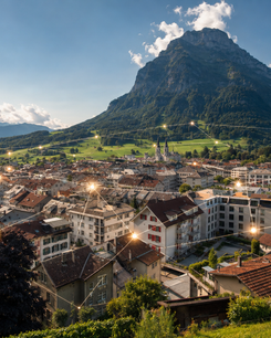 Blick über Glarus vor Bergkulisse mit leuchtenden Verbindungslinien als Symbol für digitale Vernetzung.