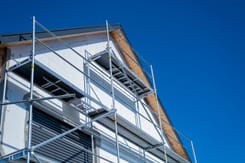 Einfamilienhaus im Bau mit Gerüst an der Fassade als Symbol für Fördergelder bei Neubau und Sanierung.