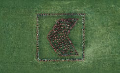 Mitarbeitende der Glarner Kantonalbank formieren sich auf einer grünen Wiese zu einem K-Signet.