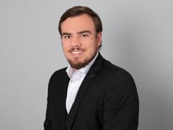 Professionelles GLKB-Porträt vor grauem Hintergrund.