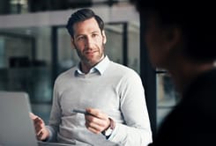 Beratungsgespräch zum Unternehmensverkauf zwischen Unternehmer und Berater im modernen Büro mit Laptop.