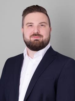 Professionelles GLKB-Porträt vor grauem Hintergrund.