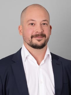 Professionelles GLKB-Porträt vor grauem Hintergrund.