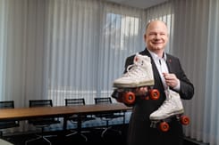 Weisse retro-rollschuhe mit roten rollen werden von einer person im Anzug in einem Büro präsentiert
