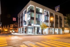 Nachtaufnahme des GLKB-Hauptsitzes in Glarus mit beleuchteter Fassade und moderner Architektur.