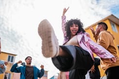 Gruppe von Freunden tanzt ausgelassen auf der Strasse in urbaner Umgebung.