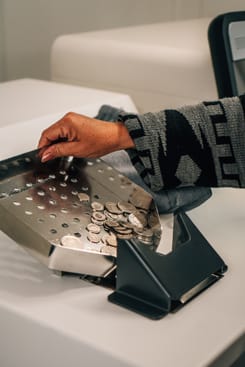 Nahaufnahme einer Hand beim Münzenzählen an einem Schalter der Glarner Kantonalbank.