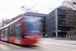Moderner bitubi Standort in Bern mit vorbeifahrendem rotem Tram vor dem Geschäftsgebäude.