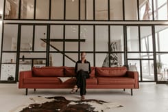 Eine Person arbeitet mit einem Laptop in einem modernen Loft mit offener Raumgestaltung und heller Arbeitsumgebung.