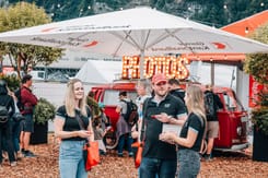 Mitarbeitende am roten VW-Photobus und GLKB-Stand,.