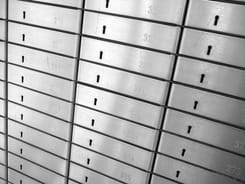 Reihe nummerierter Schrankfächer mit Schlüssellöchern in einem Banktresorraum zur sicheren Aufbewahrung.