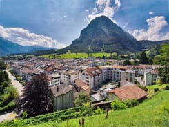 Panoramablick auf die Stadt Glarus mit Wohnhäusern und dem markanten Vorderglärnisch im Hintergrund bei Sonnenschein.