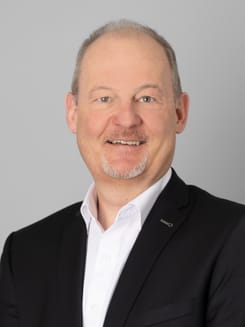 Professionelles GLKB-Porträt vor grauem Hintergrund.