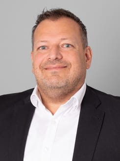 Professionelles GLKB-Porträt vor grauem Hintergrund.