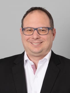 Professionelles GLKB-Porträt vor grauem Hintergrund.