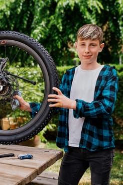 Junger Teenager reinigt ein Fahrrad im Freien – Symbolbild für Verantwortung und finanzielle Bildung.