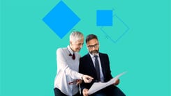 Zwei Personen in formeller Kleidung betrachten zusammen ein Dokument.