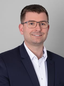 Professionelles GLKB-Porträt vor grauem Hintergrund.