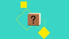 Holzwürfel mit Fragezeichen vor türkisfarbenem Hintergrund und gelben geometrischen Formen