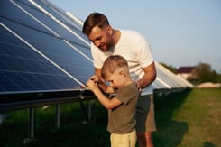 Ein Vater zeigt seinem Sohn an einer Solaranlage, wie Sonnenenergie gewonnen wird.