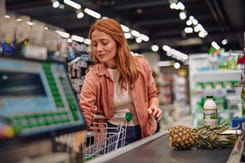 Frau kauft Lebensmittel im Supermarkt ein und legt frische Produkte auf das Kassenband