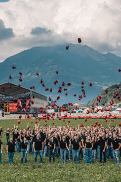 Mitarbeitende werfen rote GLKB-ESAF-Caps jubelnd in die Luft – Gruppenmoment beim GLKB-Mitarbeitendenevent.