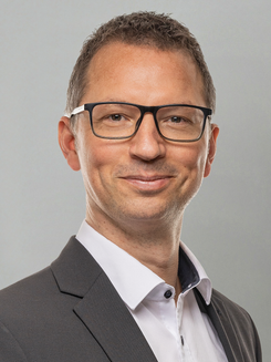 Professionelles GLKB-Porträt vor grauem Hintergrund.