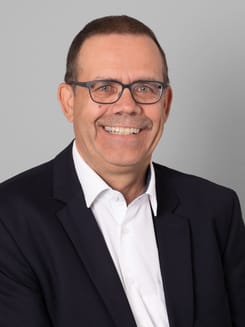 Professionelles GLKB-Porträt vor grauem Hintergrund.