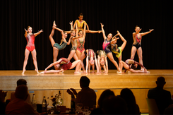 Junge Turnerinnen zeigen eine akrobatische Bühnenaufführung vor Publikum im Rahmen eines gesellschaftlichen Events.