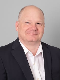 Professionelles GLKB-Porträt vor grauem Hintergrund.