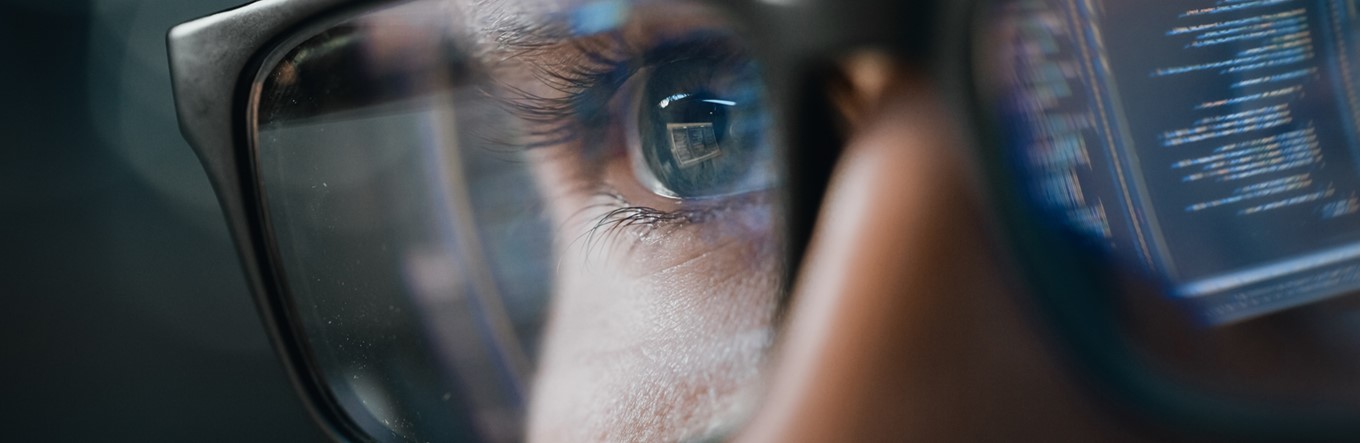 Mann mit Brille und Computer der sich darin spiegelt.