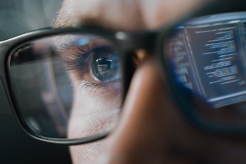 Mann mit Brille und Computer der sich darin spiegelt.