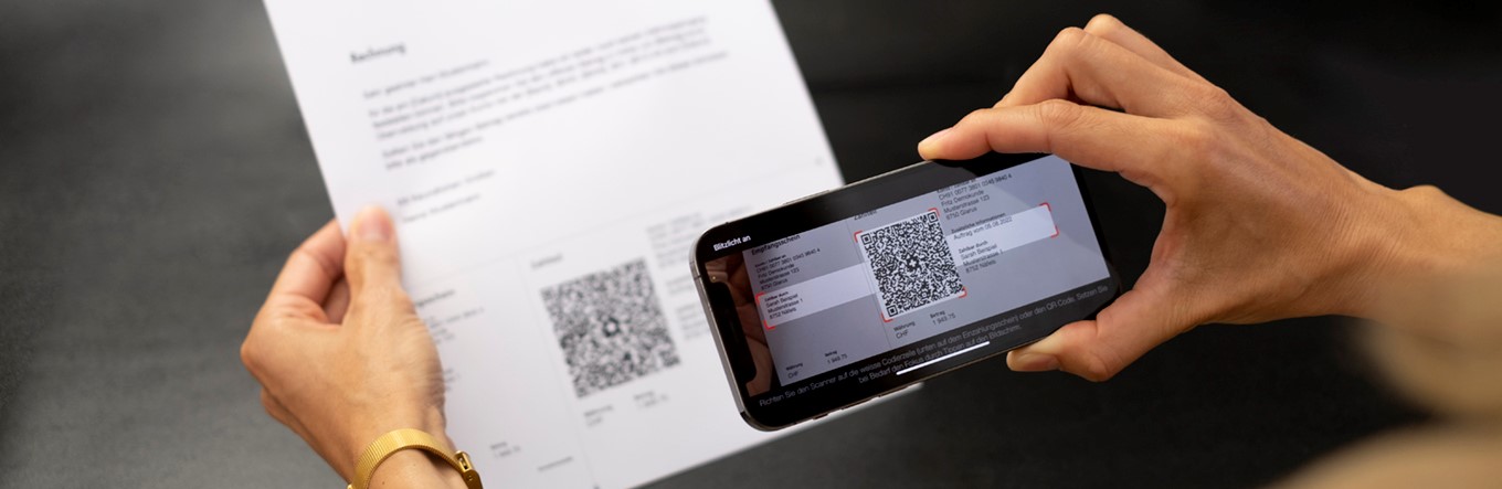 Mann scannt eine QR-Rechnung