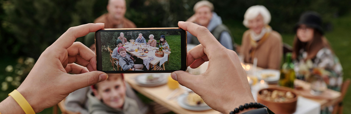 Familie am Tisch wird mit Handy fotografiert