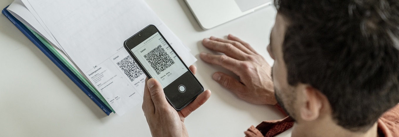 Mann scannt eine QR-Rechnung